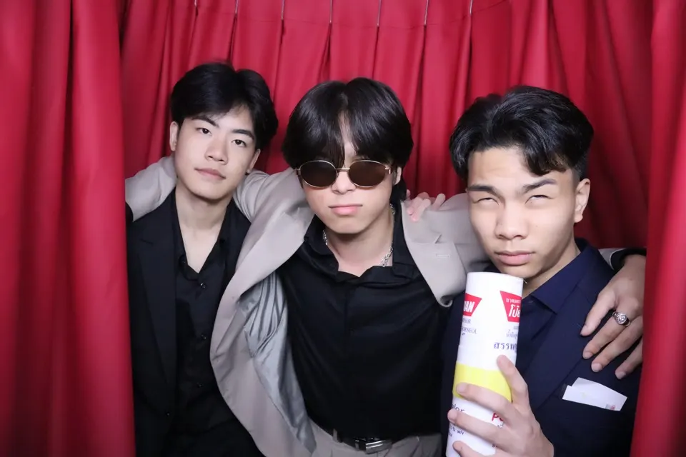 Three students in suits posing in a photo booth at D-PREP Prom 2026